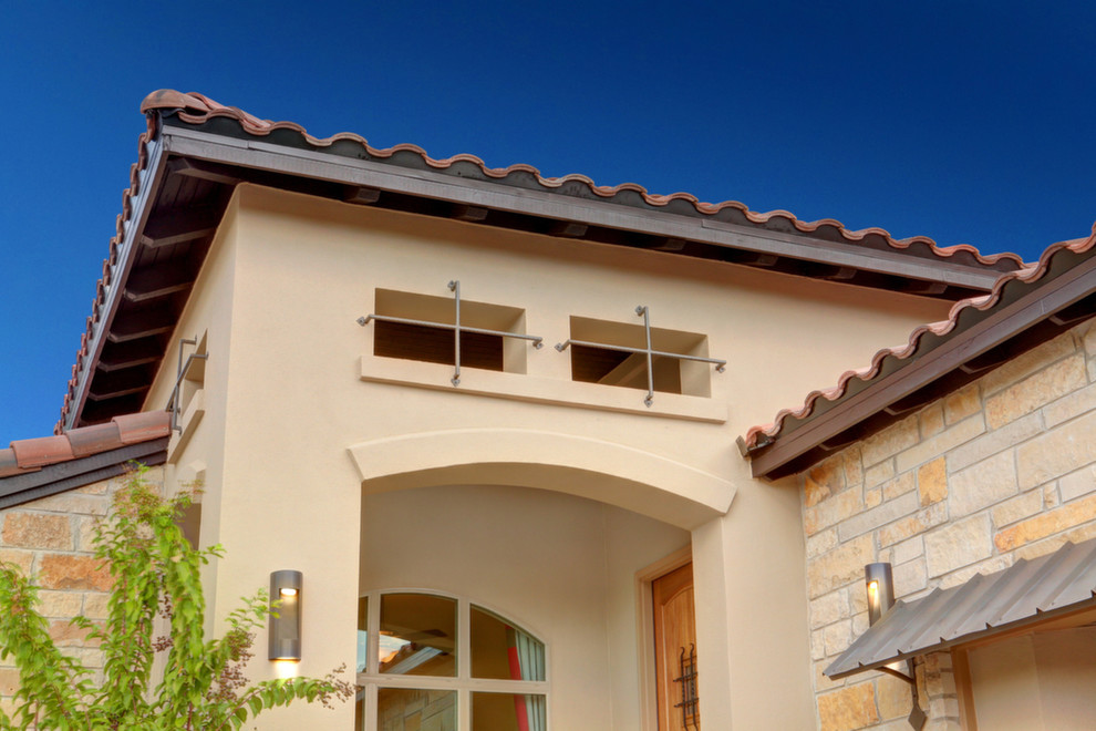 This is an example of a mediterranean bungalow house exterior in Austin with stone cladding.