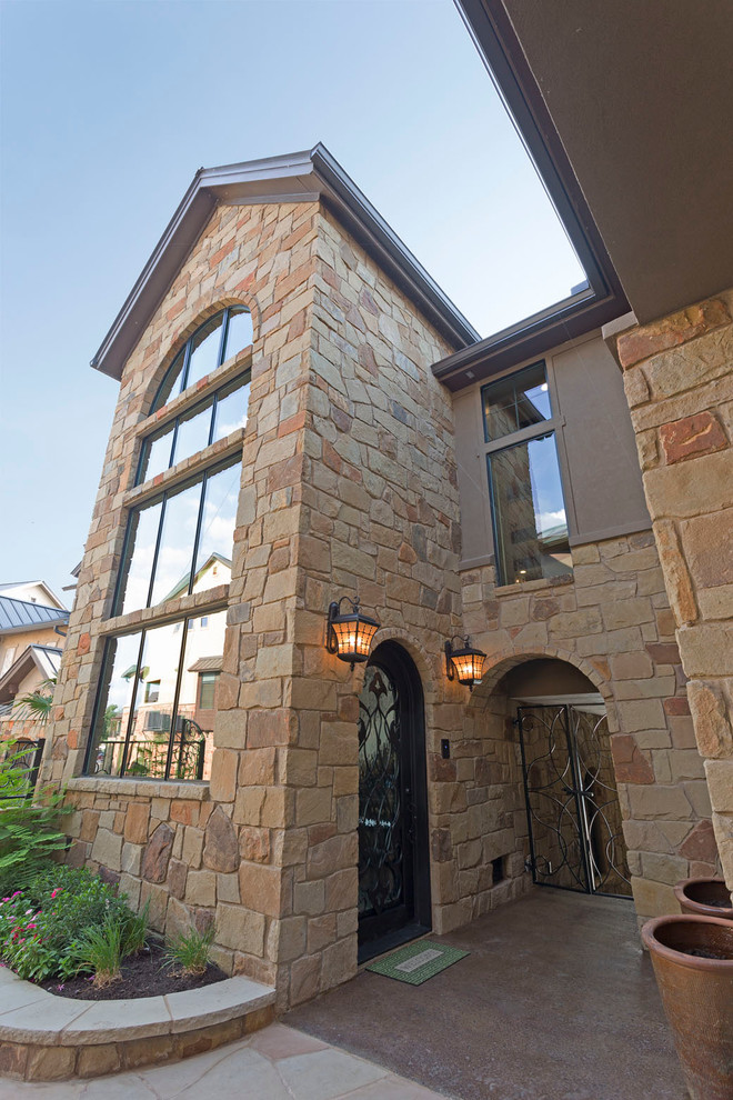 Large trendy beige two-story stone gable roof photo in Austin