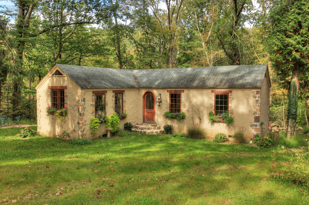 Cette image montre une petite façade de maison beige traditionnelle en stuc de plain-pied.