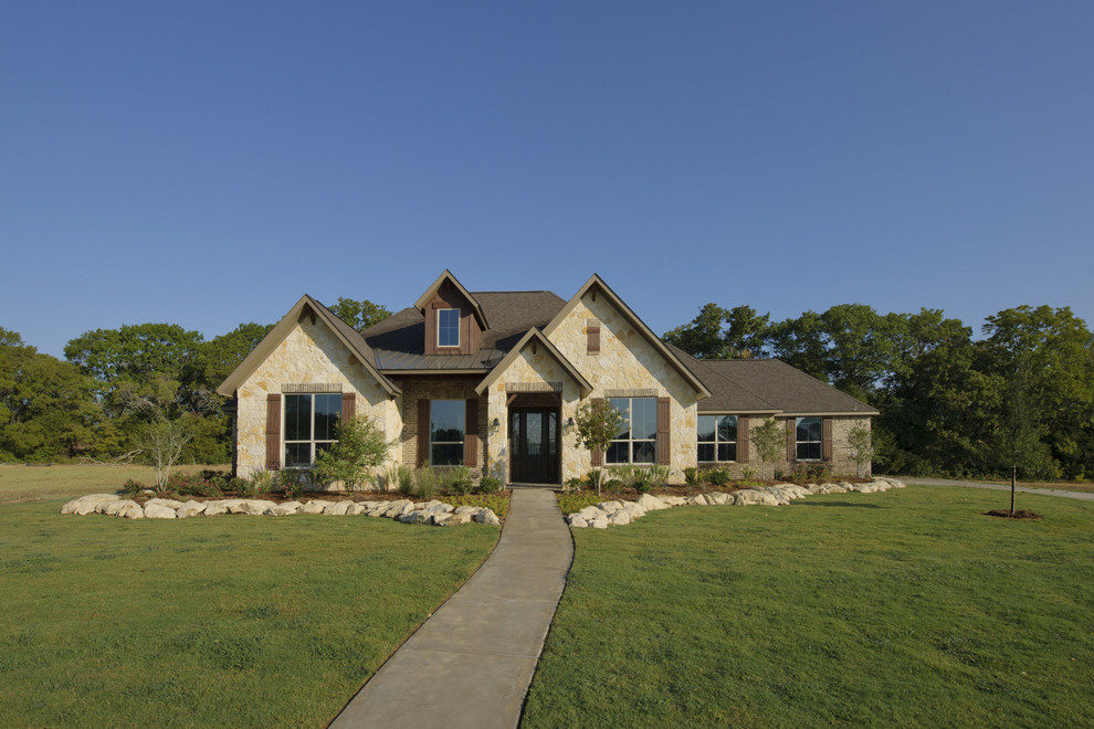 Inspiration for a mid-sized farmhouse beige two-story stone house exterior remodel in Houston with a hip roof and a shingle roof