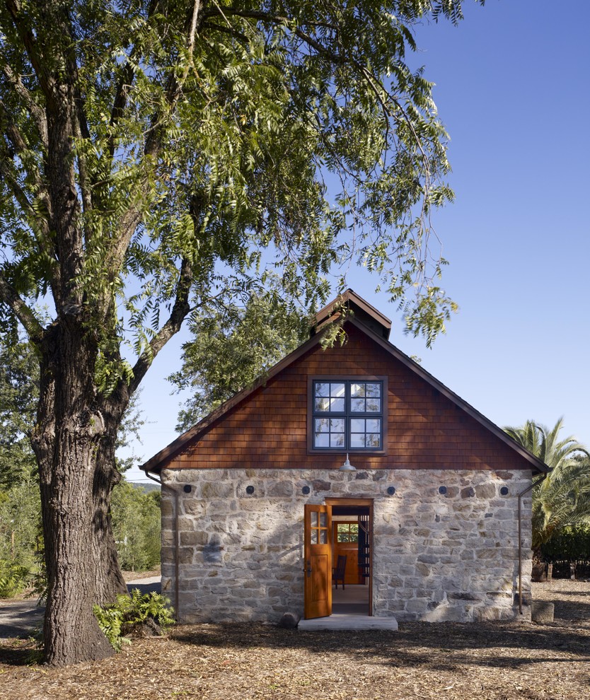 Стильный дизайн: одноэтажный, коричневый частный загородный дом в стиле рустика с облицовкой из камня и двускатной крышей - последний тренд
