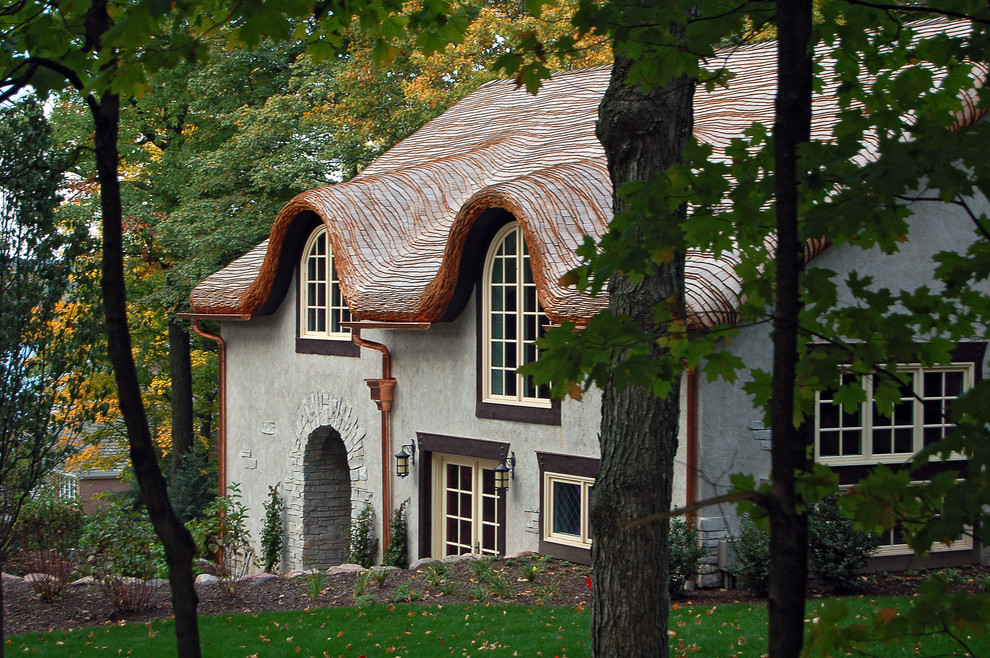 Стильный дизайн: бежевый дом в стиле кантри с облицовкой из цементной штукатурки и двускатной крышей - последний тренд