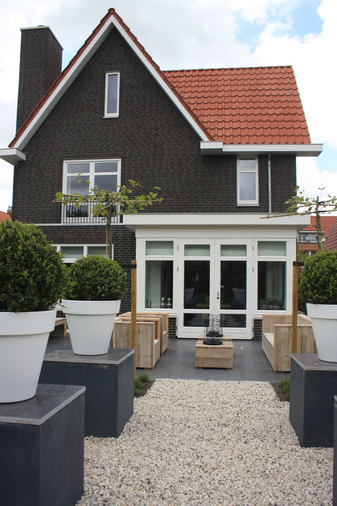 This is an example of a classic brick house exterior in Amsterdam with a pitched roof and a tiled roof.