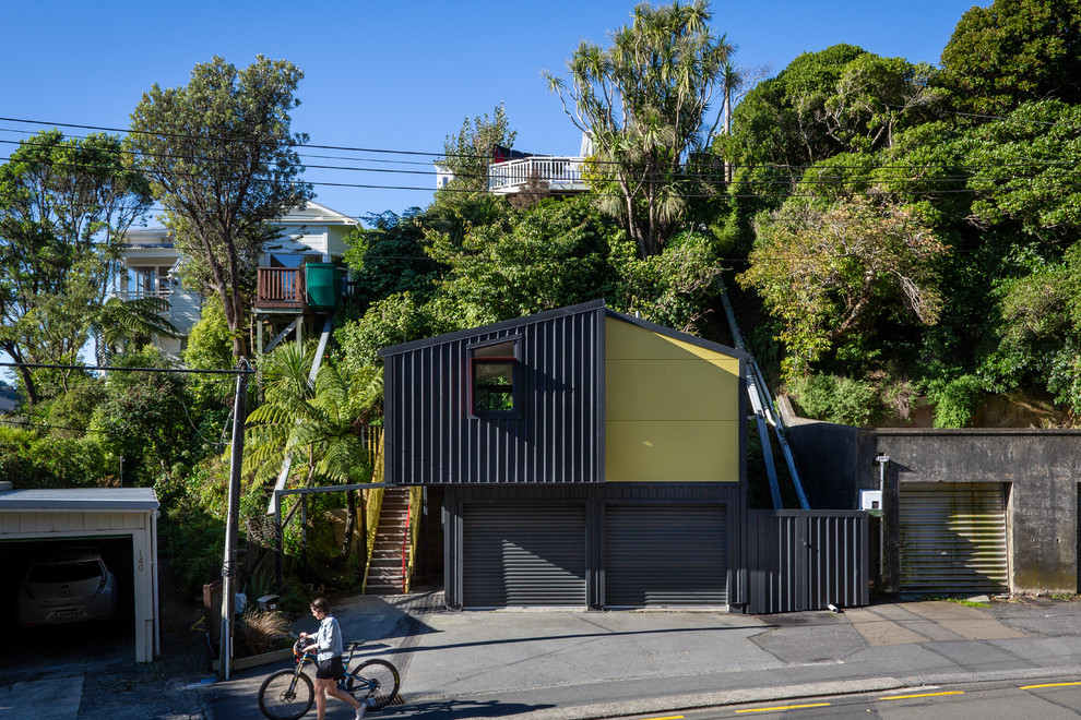 На фото: маленький, двухэтажный, разноцветный дом из контейнеров в стиле лофт с облицовкой из металла, двускатной крышей и металлической крышей для на участке и в саду