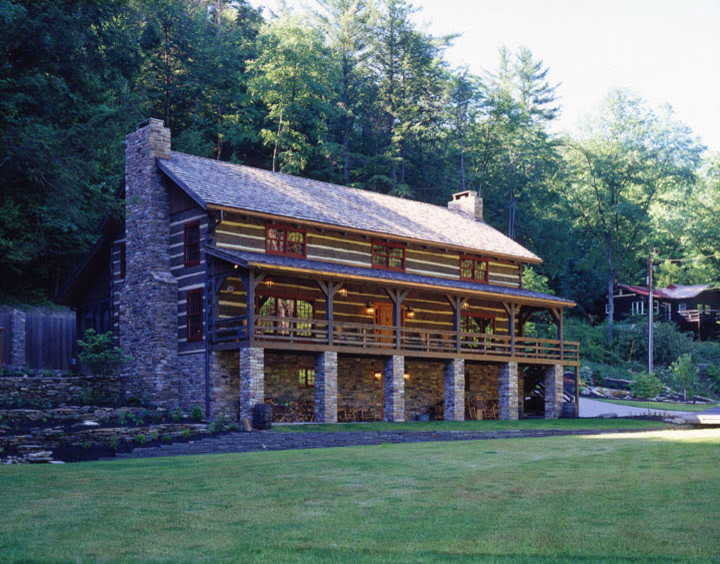 Esempio della facciata di una casa grande marrone rustica a tre piani con rivestimento in legno e falda a timpano