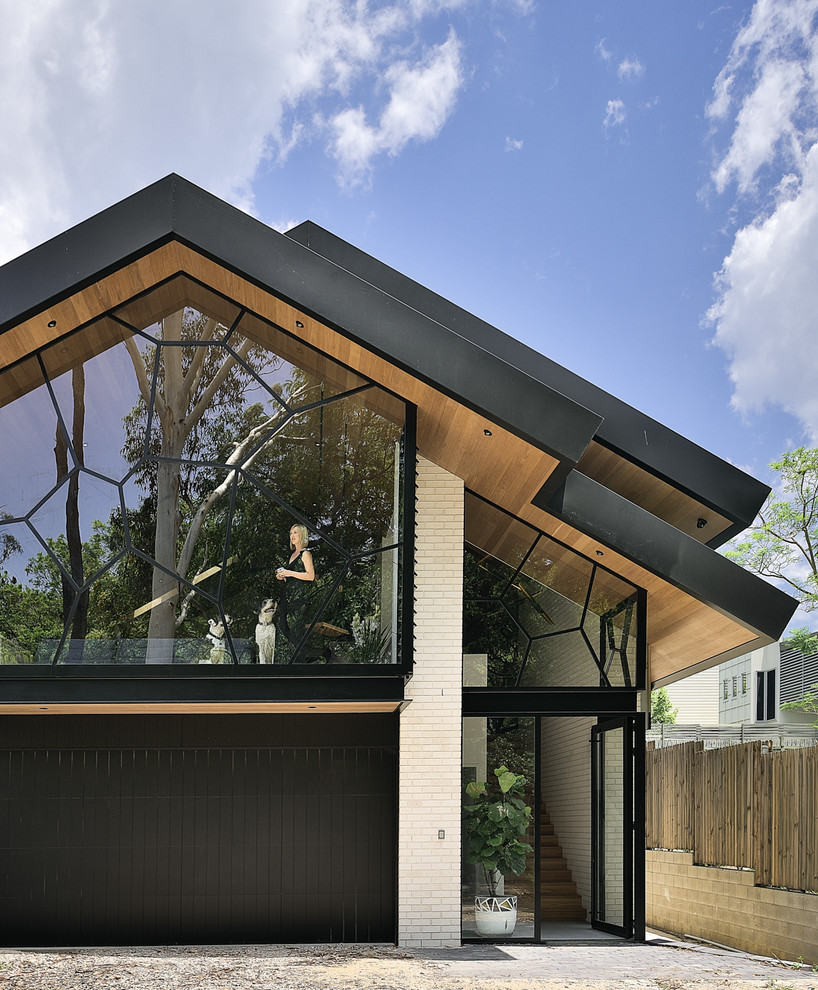Black contemporary two floor brick detached house in Brisbane with a pitched roof and a tiled roof.