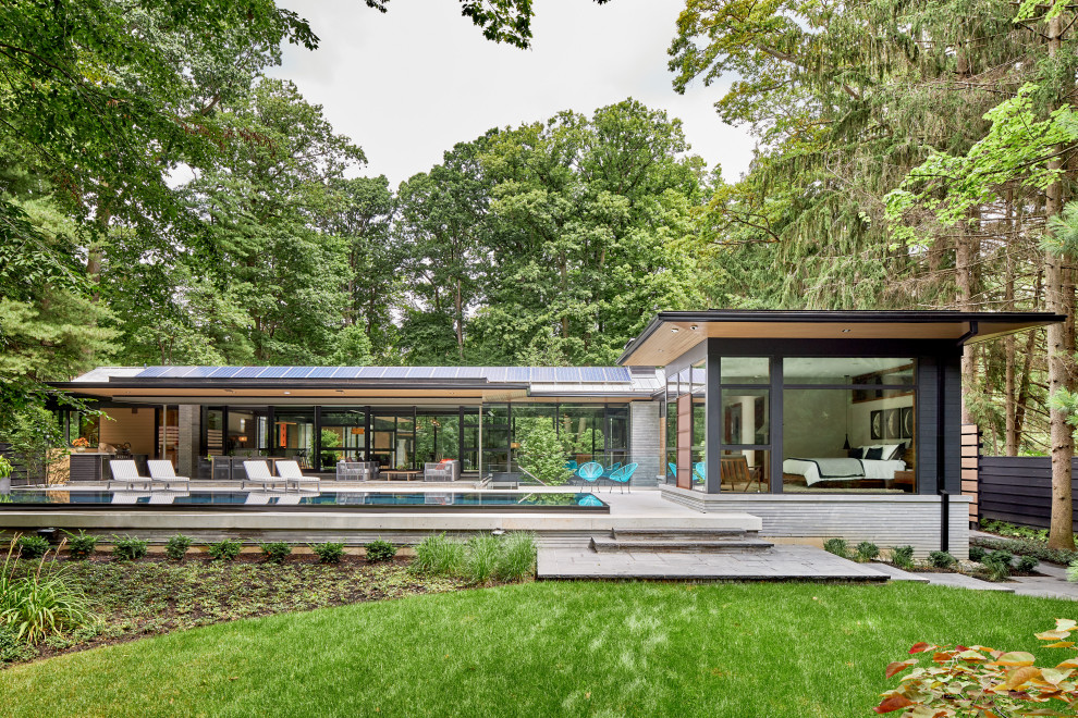 Réalisation d'une grande façade de maison multicolore design en verre de plain-pied avec un toit à deux pans et un toit en métal.