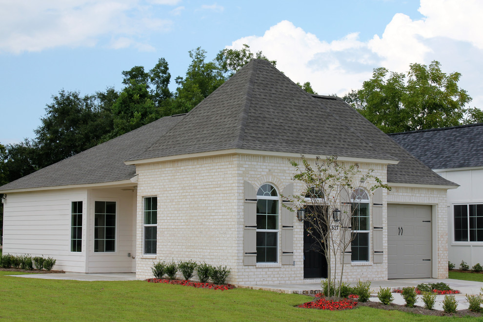 Cette photo montre une petite façade de maison beige chic en brique de plain-pied avec un toit à quatre pans.