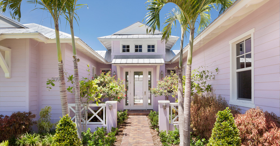 Foto della villa ampia rosa tropicale a due piani con rivestimento in legno, tetto a padiglione e copertura in metallo o lamiera