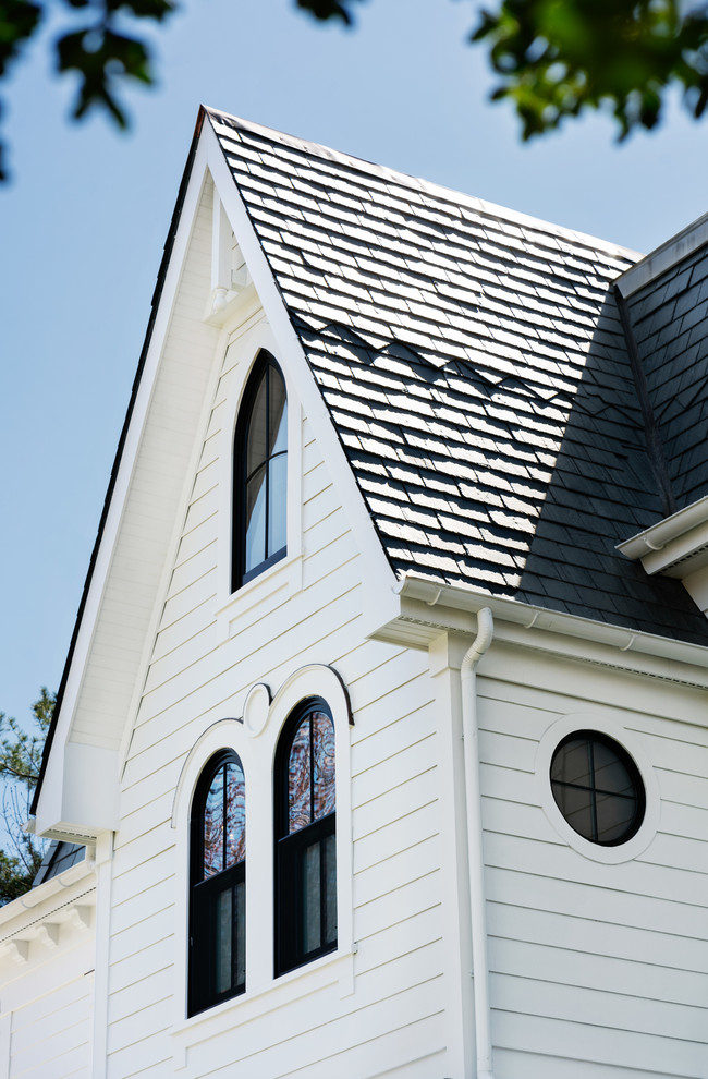 Large ornate white three-story vinyl house exterior photo in New York with a shingle roof