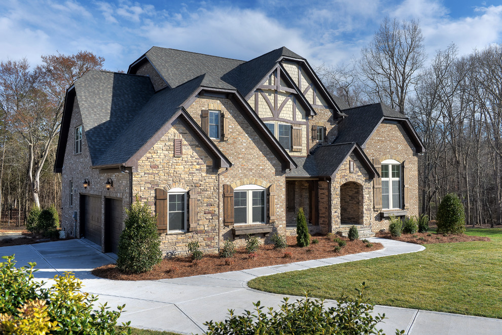 Large craftsman brown two-story brick exterior home idea in Charlotte with a clipped gable roof
