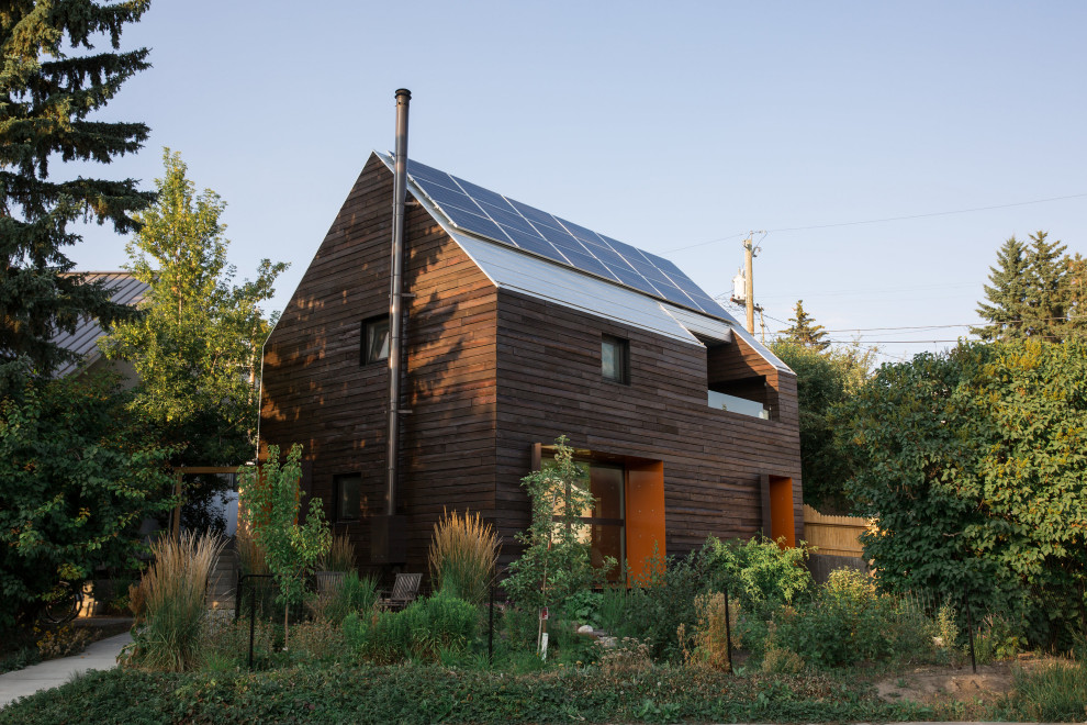 Пример оригинального дизайна: маленький, двухэтажный, деревянный, коричневый частный загородный дом в скандинавском стиле с двускатной крышей и металлической крышей для на участке и в саду