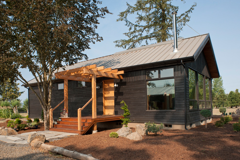 Immagine della villa piccola nera contemporanea a un piano con rivestimento in legno, tetto a padiglione e copertura in metallo o lamiera