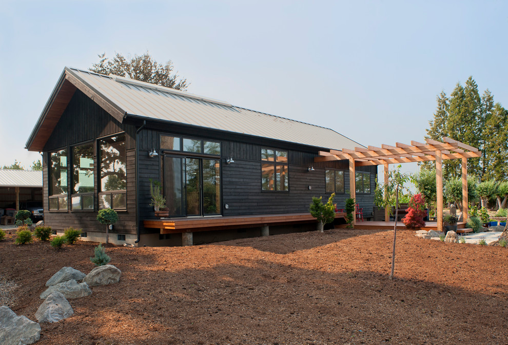 Foto på ett litet funkis svart hus, med allt i ett plan, valmat tak och tak i metall