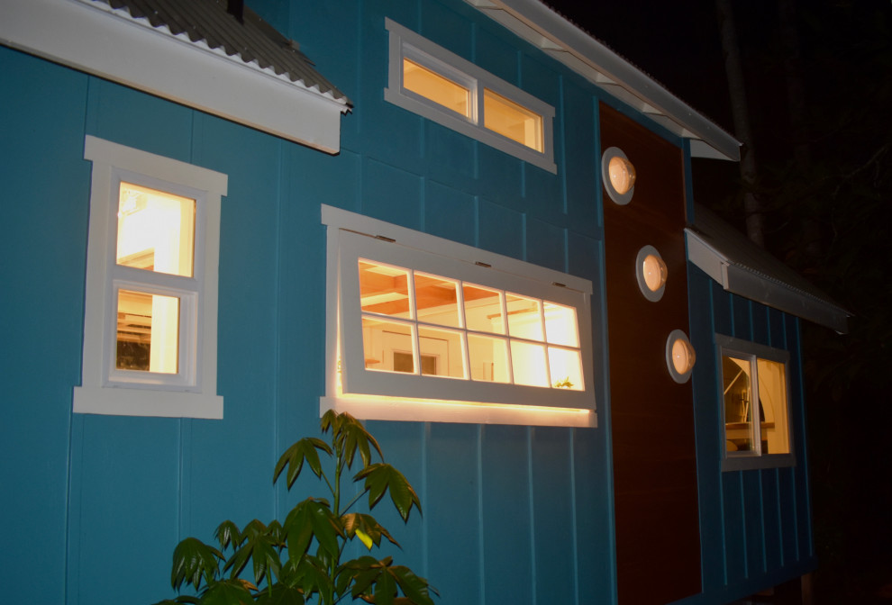 Réalisation d'une petite façade de maison bleue ethnique en bois à un étage avec un toit de Gambrel et un toit en métal.