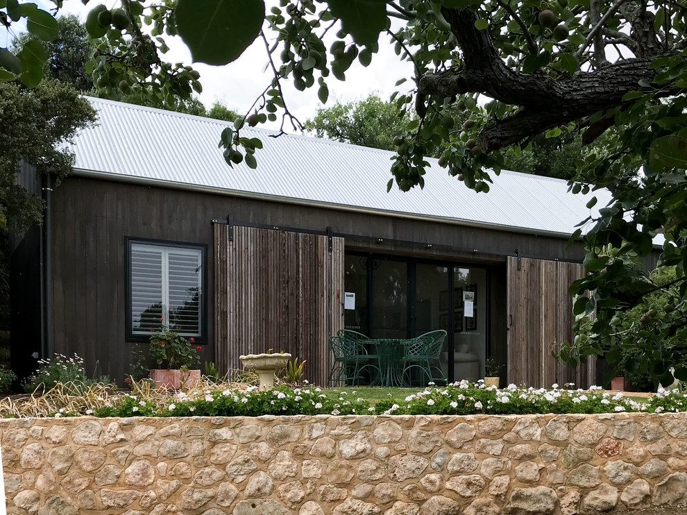 Cette image montre une petite façade de maison noire chalet en bois de plain-pied avec un toit à deux pans et un toit en métal.