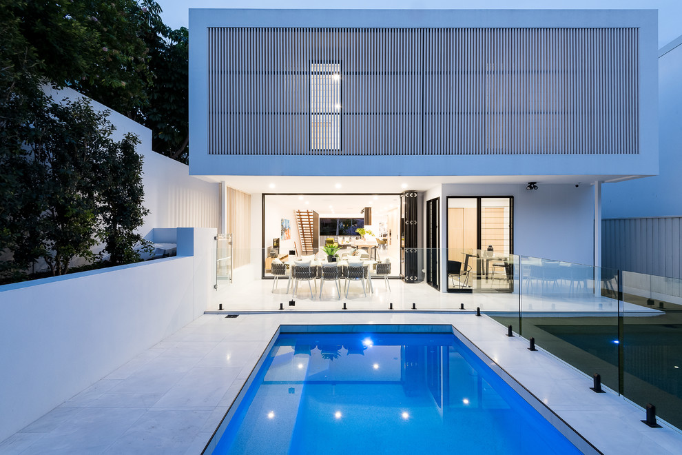 Photo of a medium sized and white modern brick detached house in Brisbane with three floors, a pitched roof and a metal roof.