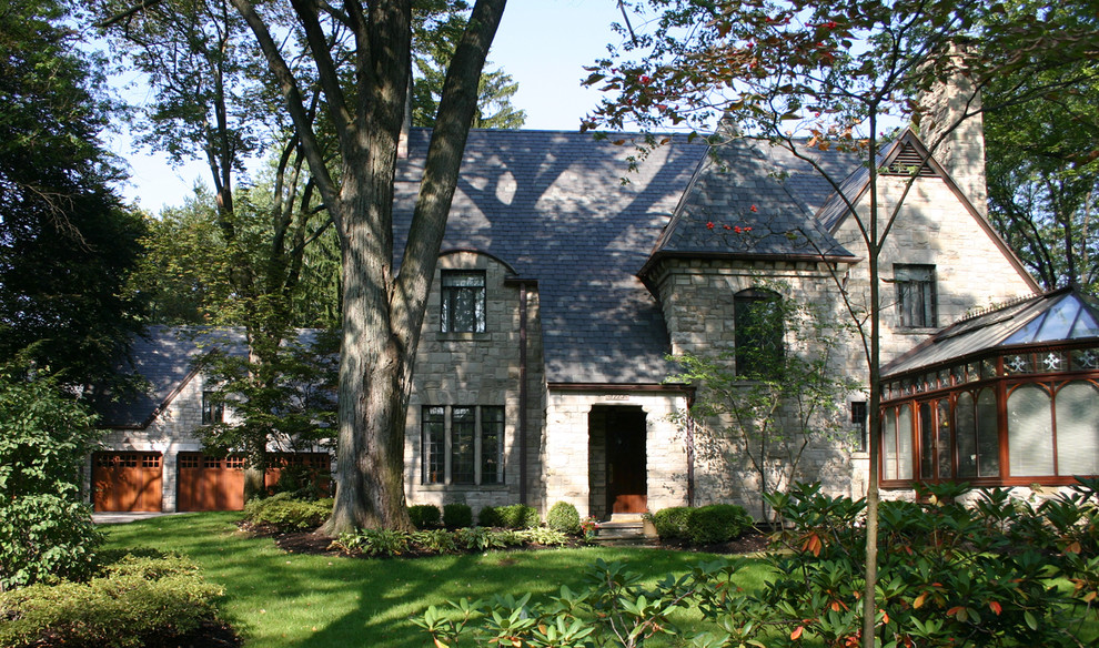 Пример оригинального дизайна: двухэтажный частный загородный дом среднего размера в классическом стиле с облицовкой из камня, двускатной крышей и черепичной крышей