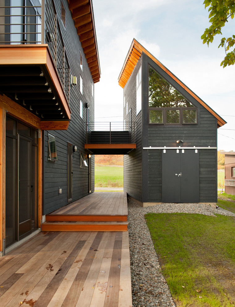 Cette image montre une façade de maison grise design en bois à un étage et de taille moyenne avec un toit en appentis et un toit en métal.