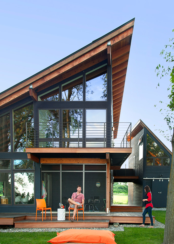 Modelo de fachada de casa gris actual de tamaño medio de dos plantas con revestimiento de madera, tejado de un solo tendido y tejado de metal