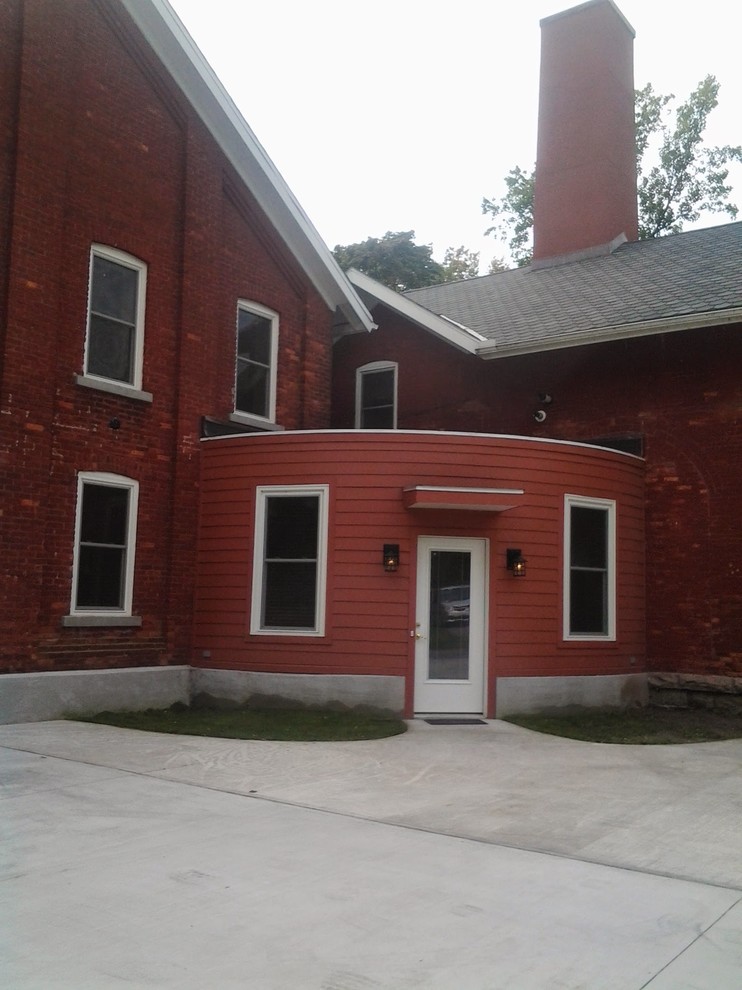 Aménagement d'une façade de maison rouge industrielle en panneau de béton fibré de taille moyenne et de plain-pied avec un toit plat.