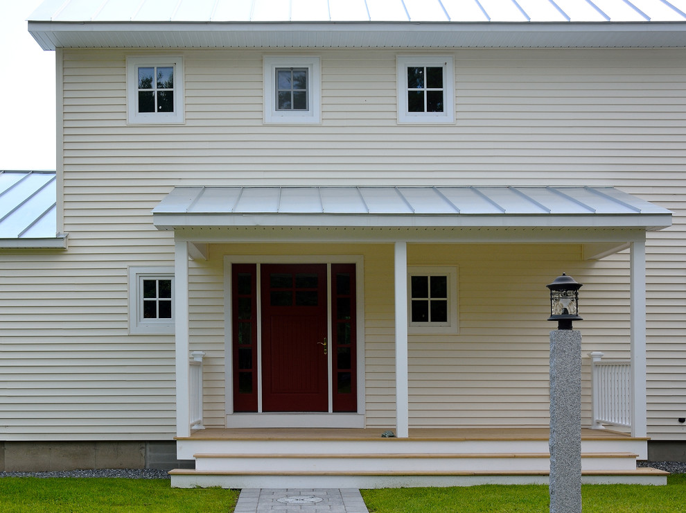 Mittelgroßes, Zweistöckiges Landhausstil Haus mit Vinylfassade und gelber Fassadenfarbe in Portland Maine