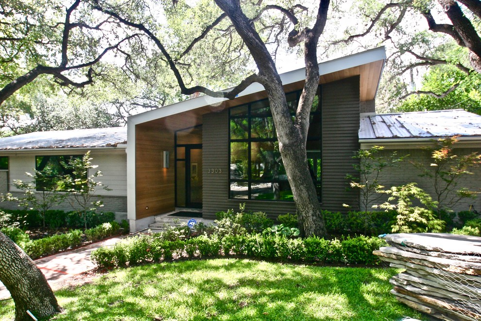 Mittelgroßes, Einstöckiges Mid-Century Einfamilienhaus mit Mix-Fassade, grauer Fassadenfarbe, Pultdach und Blechdach in Austin