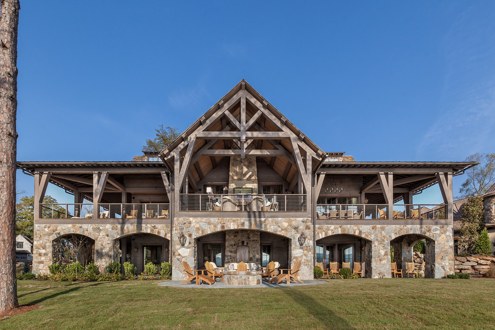 Ispirazione per la villa rustica a due piani con rivestimento in pietra e tetto a capanna
