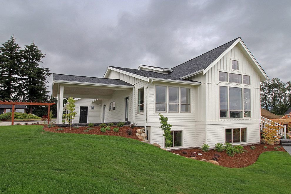 Immagine della facciata di una casa grande bianca country a tre piani con rivestimento con lastre in cemento e tetto a capanna