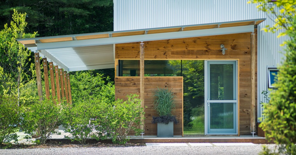 На фото: маленький, одноэтажный, белый частный загородный дом в стиле модернизм с облицовкой из металла и двускатной крышей для на участке и в саду с
