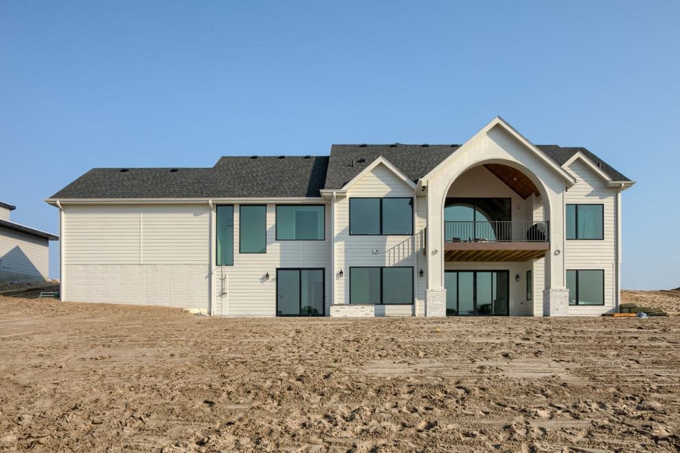 Foto della villa bianca country a un piano con rivestimento in mattoni, tetto a capanna e copertura in metallo o lamiera