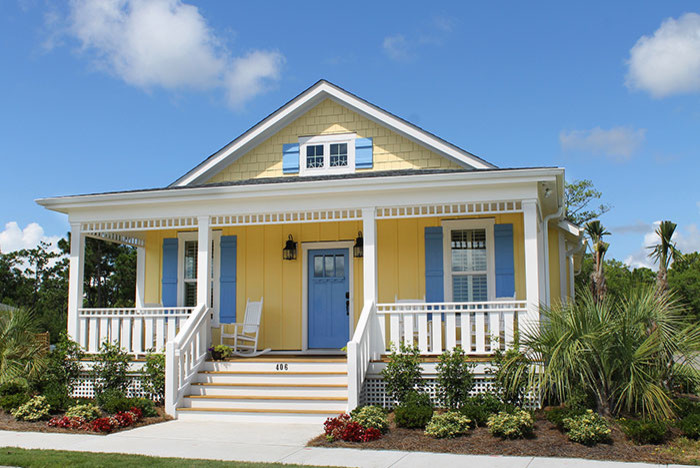Esempio della facciata di una casa piccola gialla stile marinaro a due piani con rivestimento in legno e tetto a capanna
