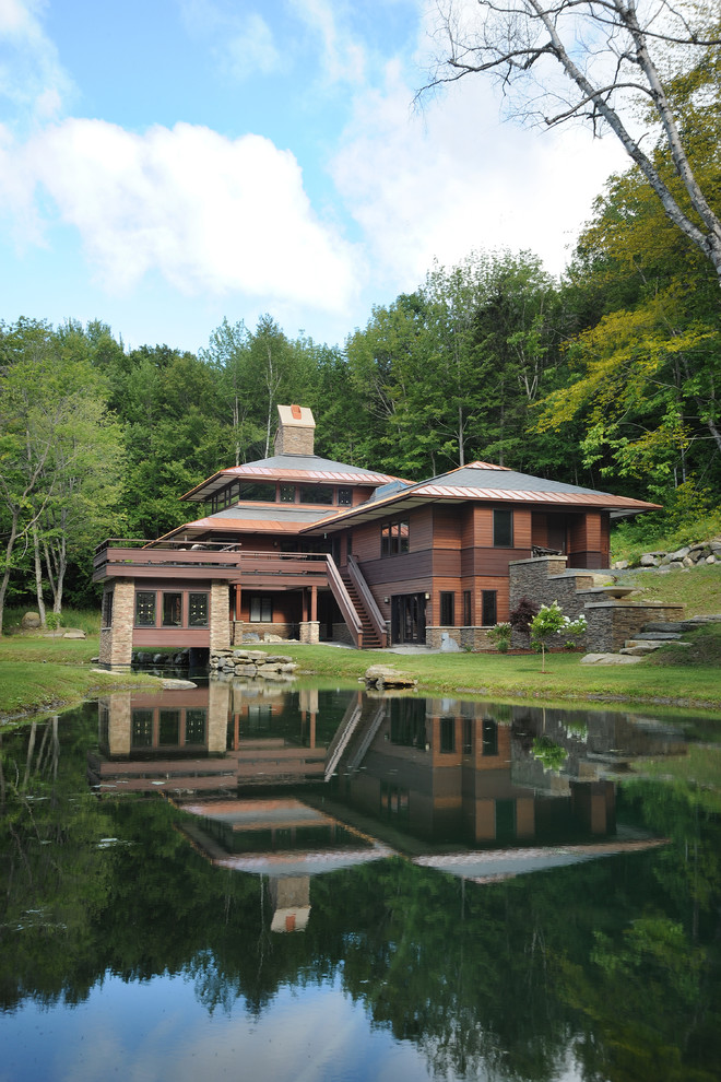 Imagen de fachada marrón de estilo americano grande de tres plantas con revestimiento de madera y tejado a cuatro aguas