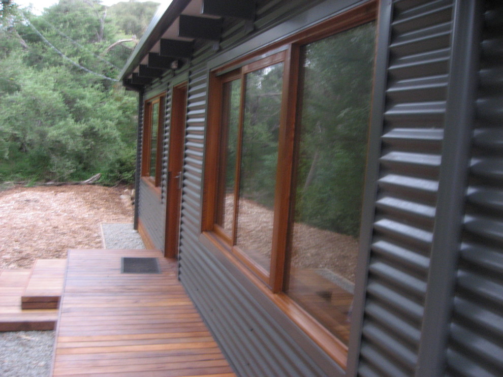 Immagine della villa piccola grigia contemporanea a un piano con rivestimento in metallo, tetto a capanna e copertura in metallo o lamiera