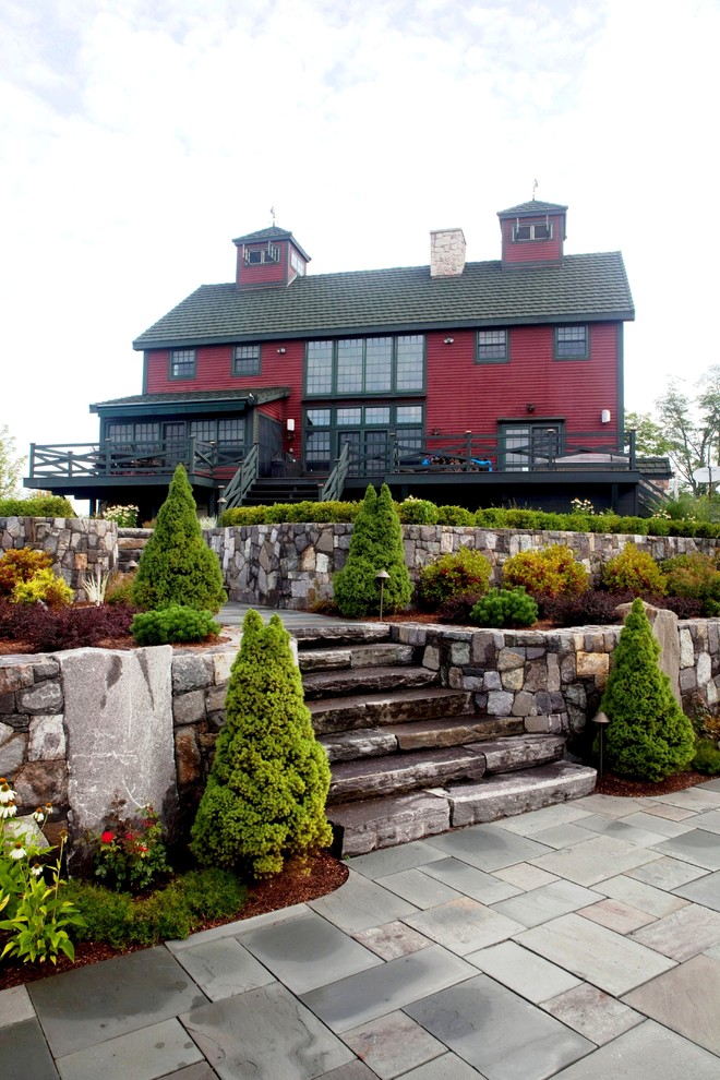 Aménagement d'une grande façade de maison rouge montagne en bois à un étage avec un toit à deux pans.