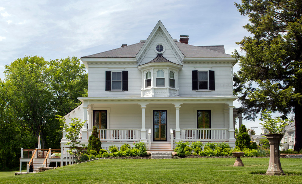 Esempio della facciata di una casa grande bianca country a due piani con rivestimento in legno