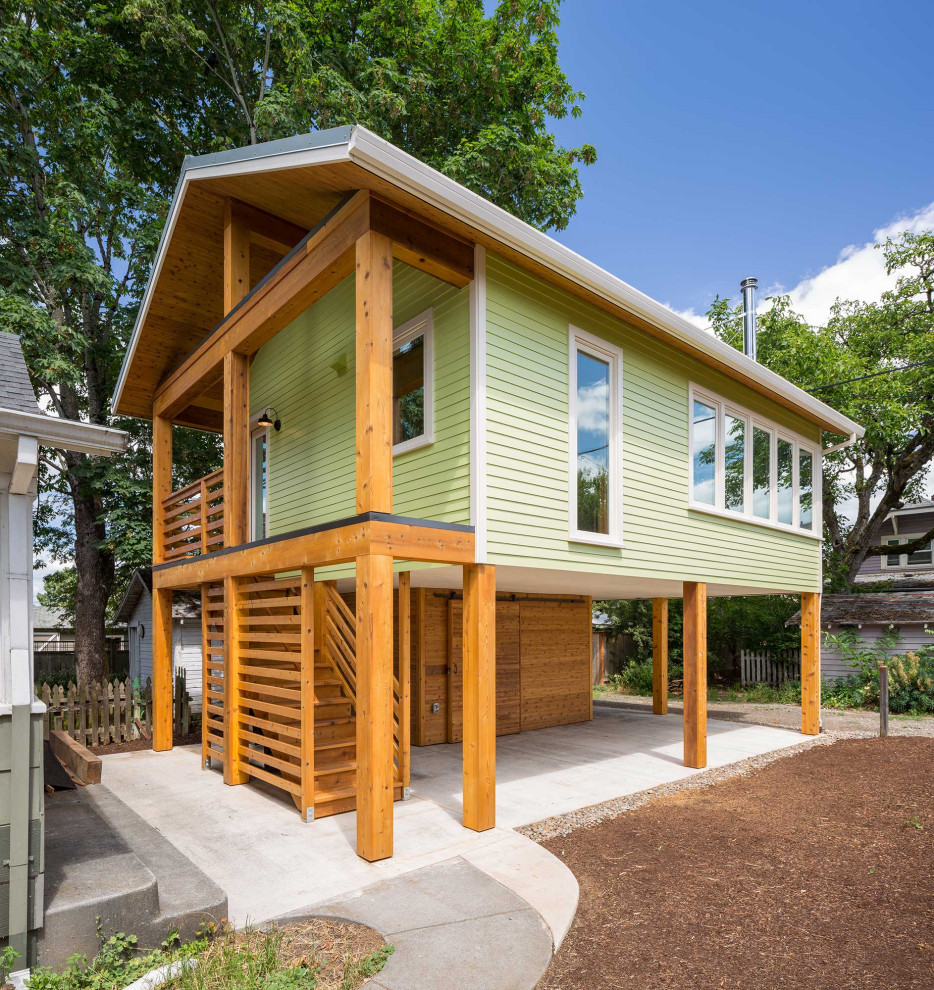 На фото: маленький, двухэтажный, зеленый частный загородный дом в стиле модернизм с облицовкой из ЦСП, двускатной крышей и металлической крышей для на участке и в саду с