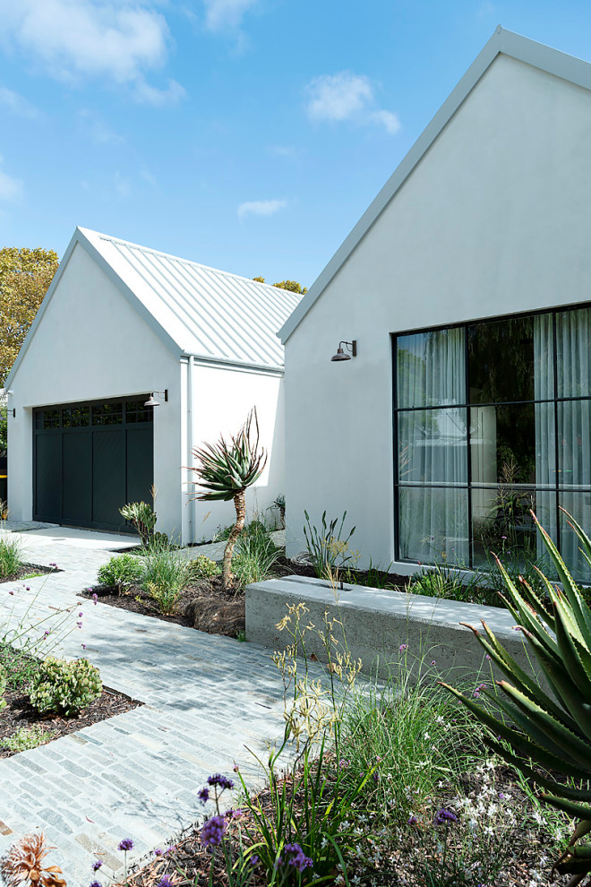 Inspiration pour une grande façade de maison blanche design en pierre à un étage avec un toit à deux pans et un toit en métal.
