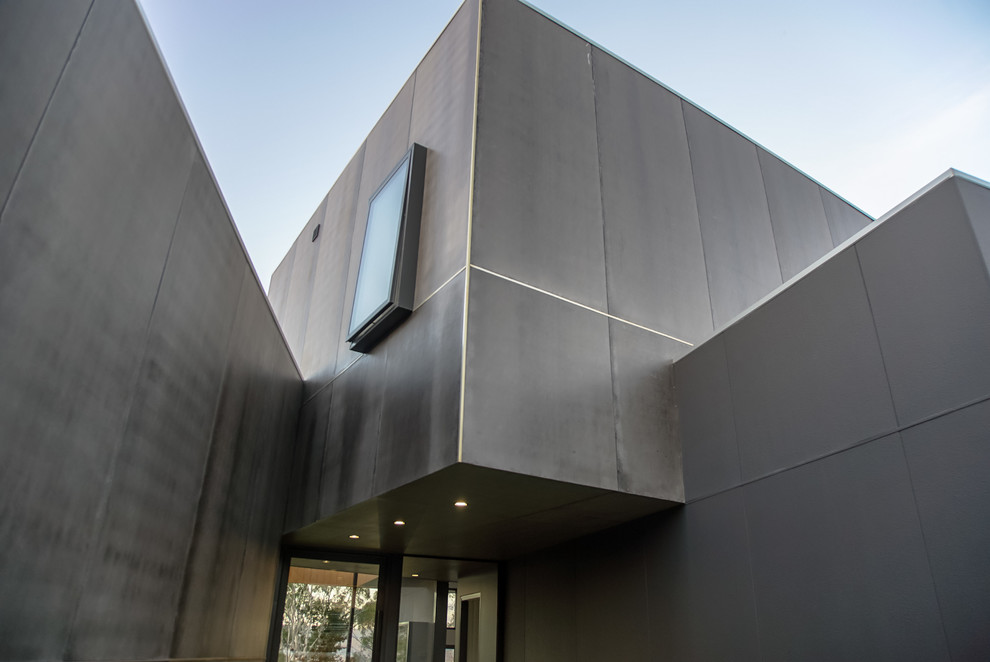 This is an example of a large and gey contemporary house exterior in Hobart with three floors and concrete fibreboard cladding.