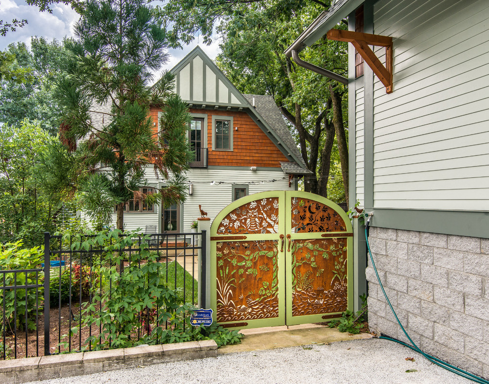 На фото: маленький, двухэтажный, зеленый дом в стиле кантри с облицовкой из ЦСП, двускатной крышей и крышей из гибкой черепицы для на участке и в саду с