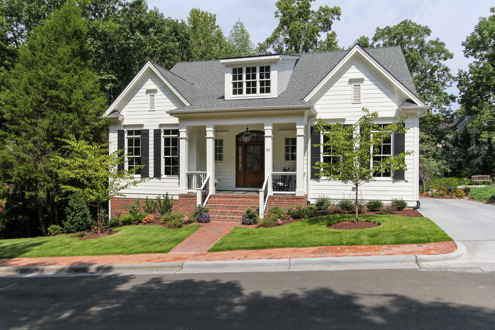 Cette image montre une façade de maison blanche traditionnelle en panneau de béton fibré à un étage avec un toit à deux pans.