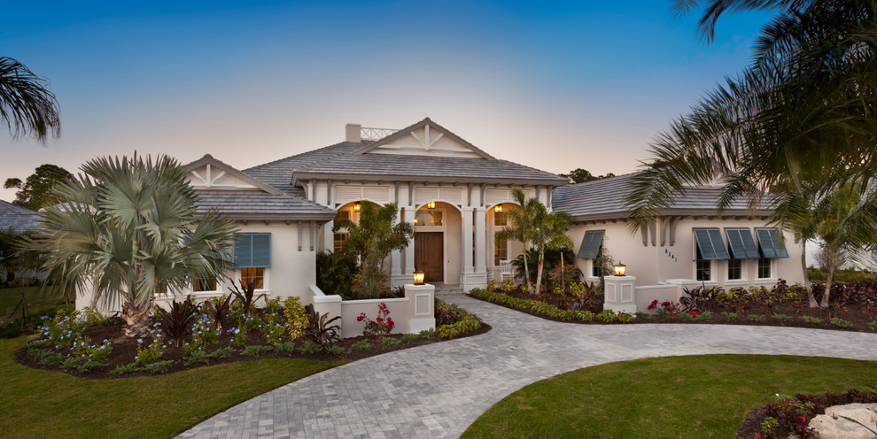 Diseño de fachada de casa beige tropical extra grande de una planta con revestimiento de estuco y tejado de teja de madera