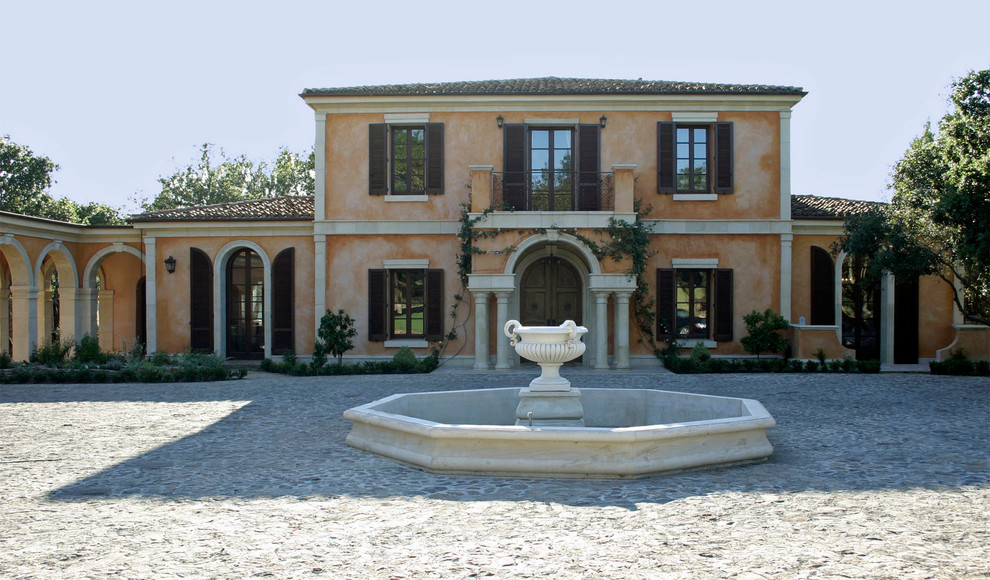 Cette photo montre une grande façade de maison méditerranéenne en béton à un étage avec un toit à deux pans.