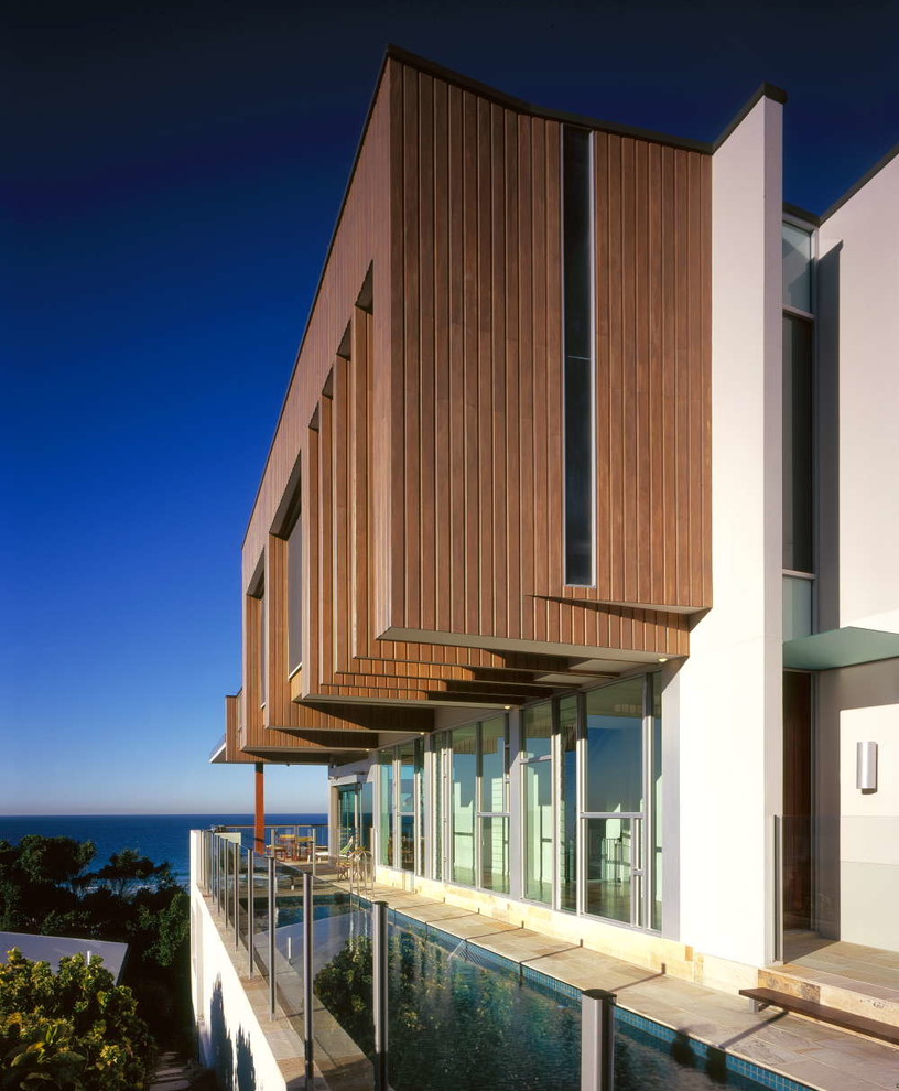 Photo of a white contemporary two floor house exterior in Gold Coast - Tweed with wood cladding and a flat roof.