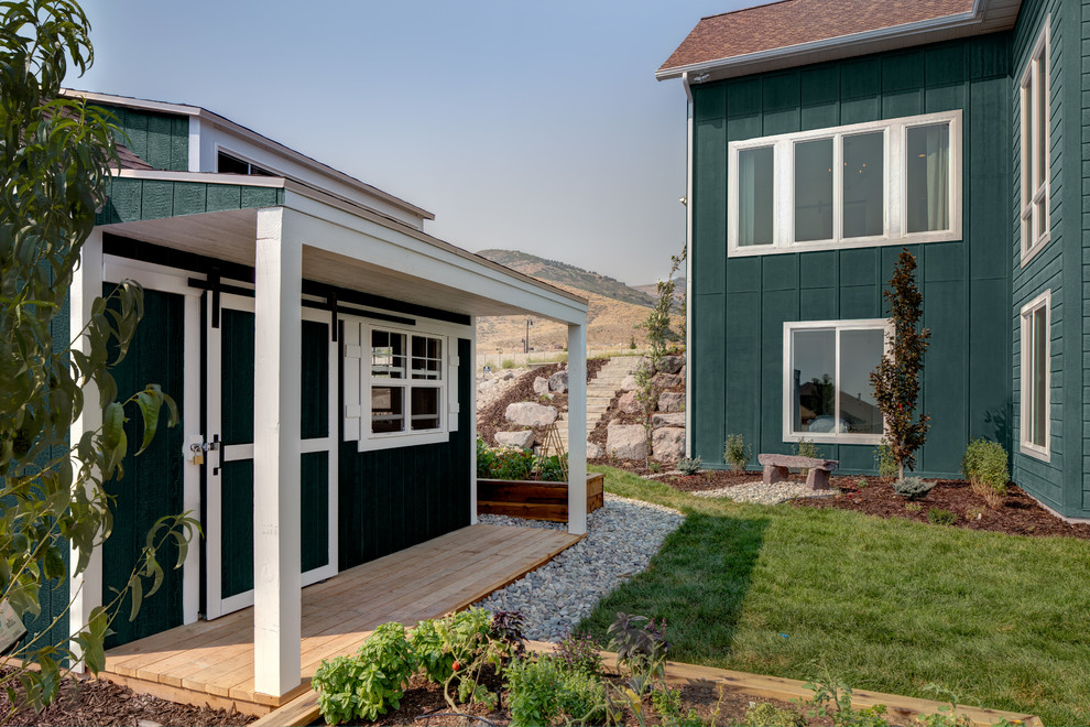 На фото: двухэтажный, зеленый частный загородный дом среднего размера в стиле кантри с облицовкой из ЦСП и крышей из смешанных материалов