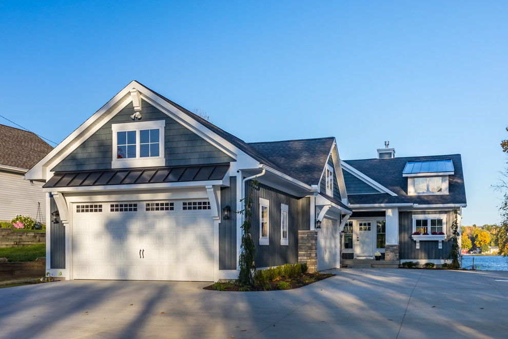 This is an example of a medium sized and blue beach style two floor house exterior in Grand Rapids with vinyl cladding and a shingle roof.