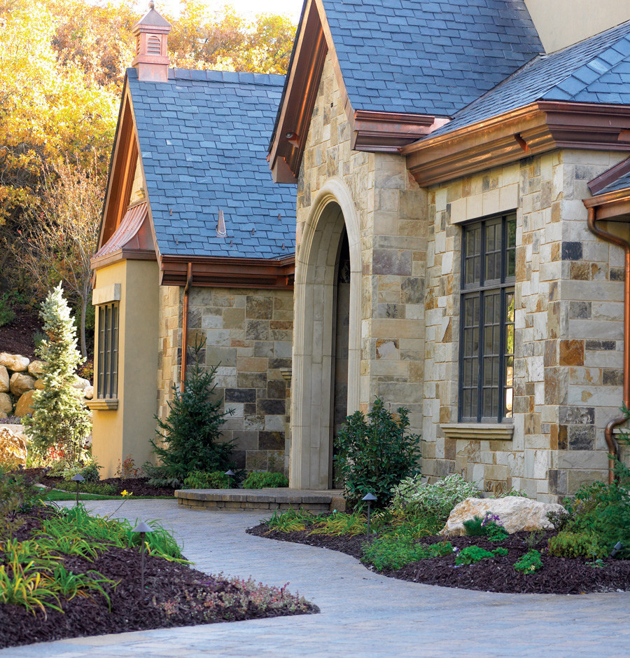 Diseño de fachada de casa beige contemporánea grande de dos plantas con revestimiento de piedra, tejado a dos aguas y tejado de teja de madera