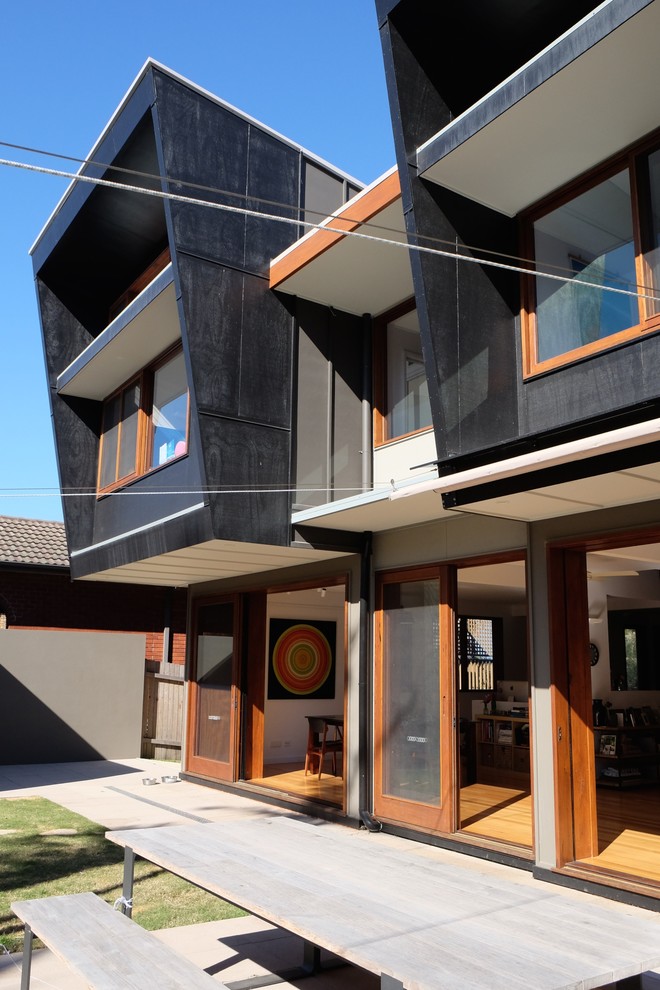 Стильный дизайн: двухэтажный, черный дом среднего размера в современном стиле с комбинированной облицовкой и плоской крышей - последний тренд