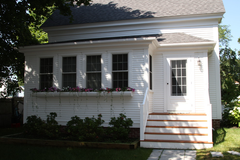 Esempio della facciata di una casa piccola bianca classica a due piani con rivestimento in legno