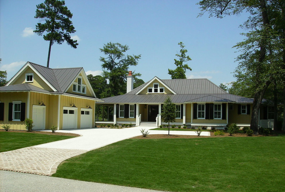 Esempio della facciata di una casa grande gialla classica a un piano con tetto a capanna